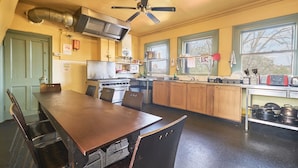 A kitchen with a dining table, chairs, a stove, and a ceiling fan. - Hootananny Hostel (London)