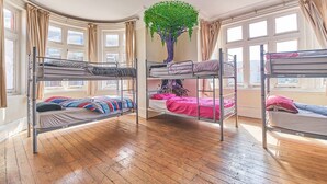 A dormitory room with bunk beds, a large window, and a tree mural on the wall. - Hootananny Hostel (London)