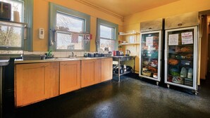 A kitchen with wooden cabinets, a sink, a stove, and two refrigerators. - Hootananny Hostel (London)