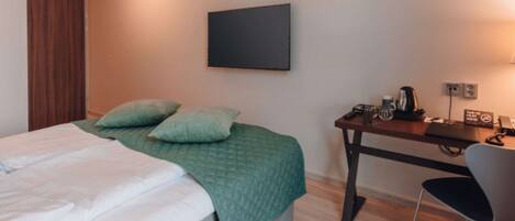 A bedroom with a bed, a desk, and a chair.