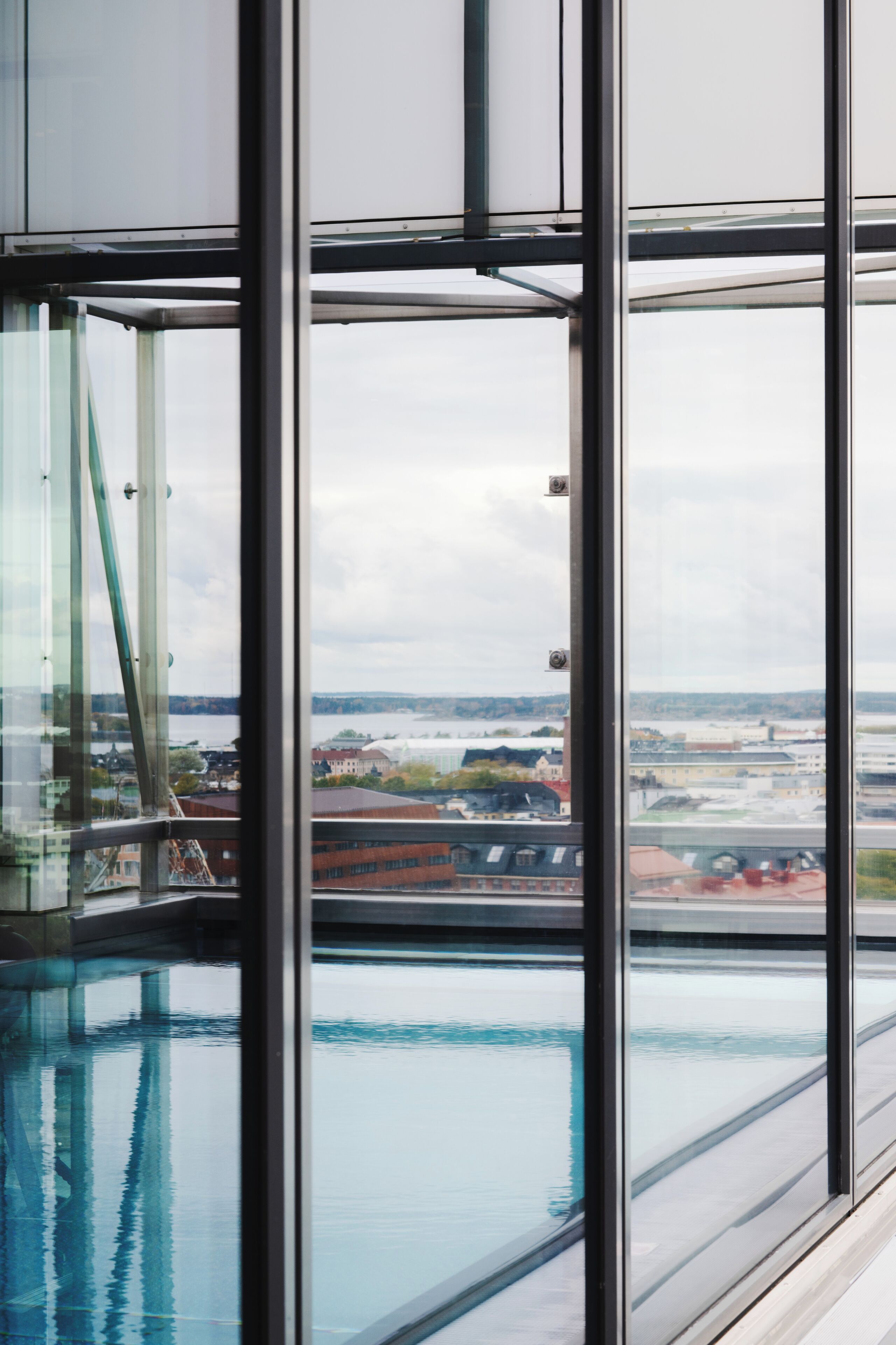 Un bâtiment moderne doté de grandes fenêtres, d’une piscine intérieure et offrant une vue sur le paysage urbain.
