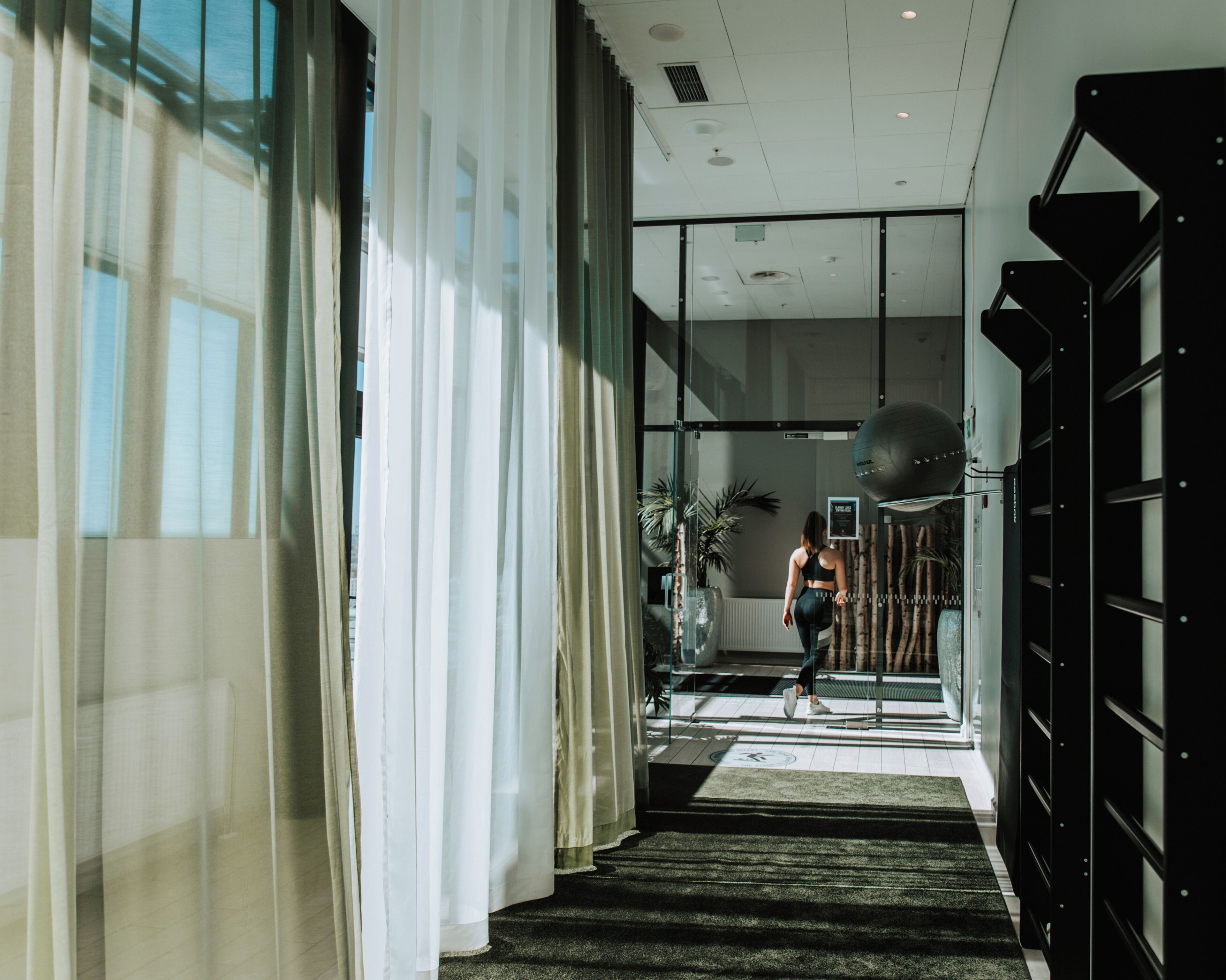 A modern hotel lobby with a staircase, large windows, and a reception desk.