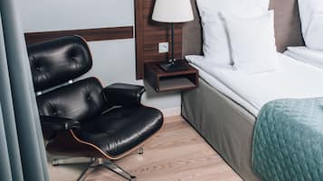 A hotel room with a bed, a chair, a nightstand, and a lamp.