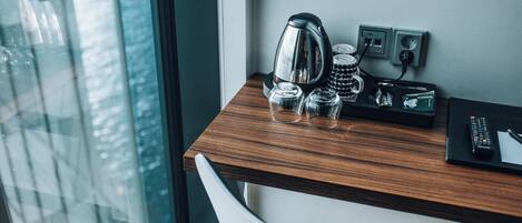 A wooden desk with a kettle, a mug, and a remote control.