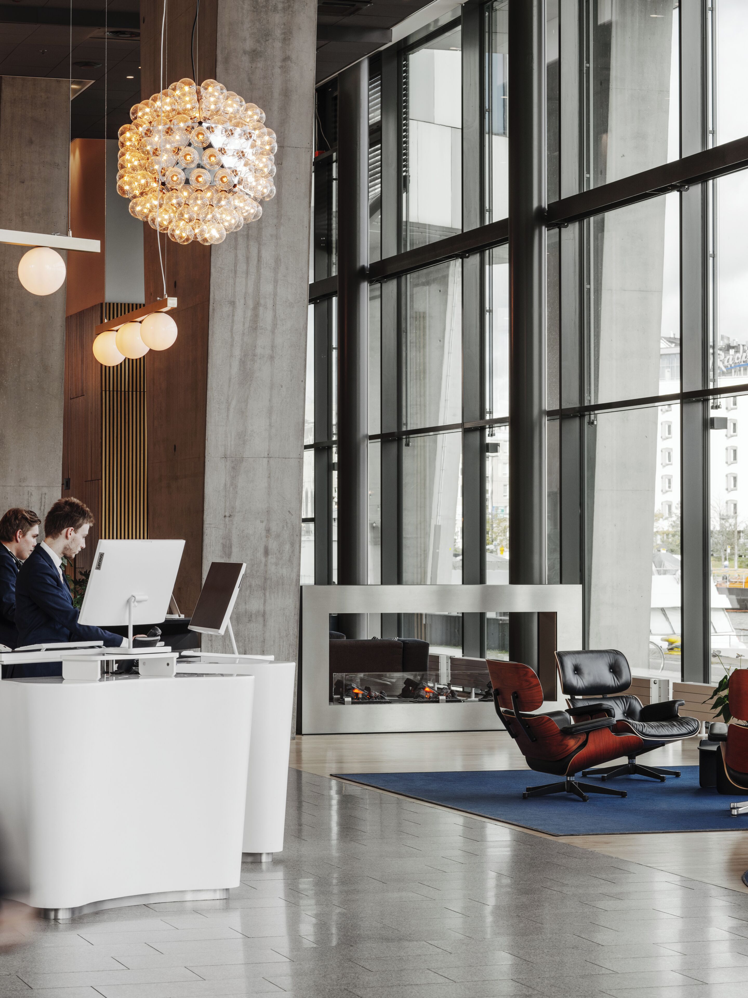 A modern office space with large windows, a reception desk, and a seating area with chairs.