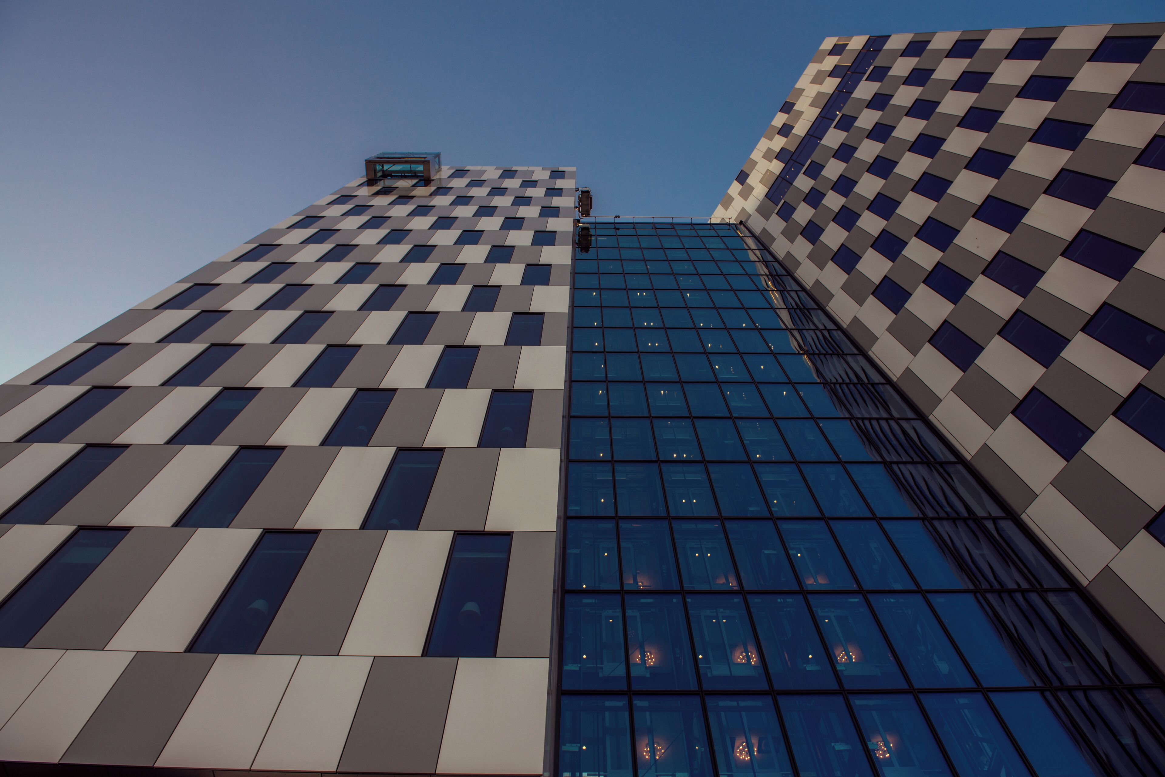 Ein modernes Hochhaus mit Schachbrettmuster-Fassade und spiegelnden Glasfenstern.