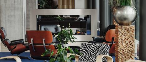 A modern lounge area with leather chairs, a blue carpet, and a large potted plant.