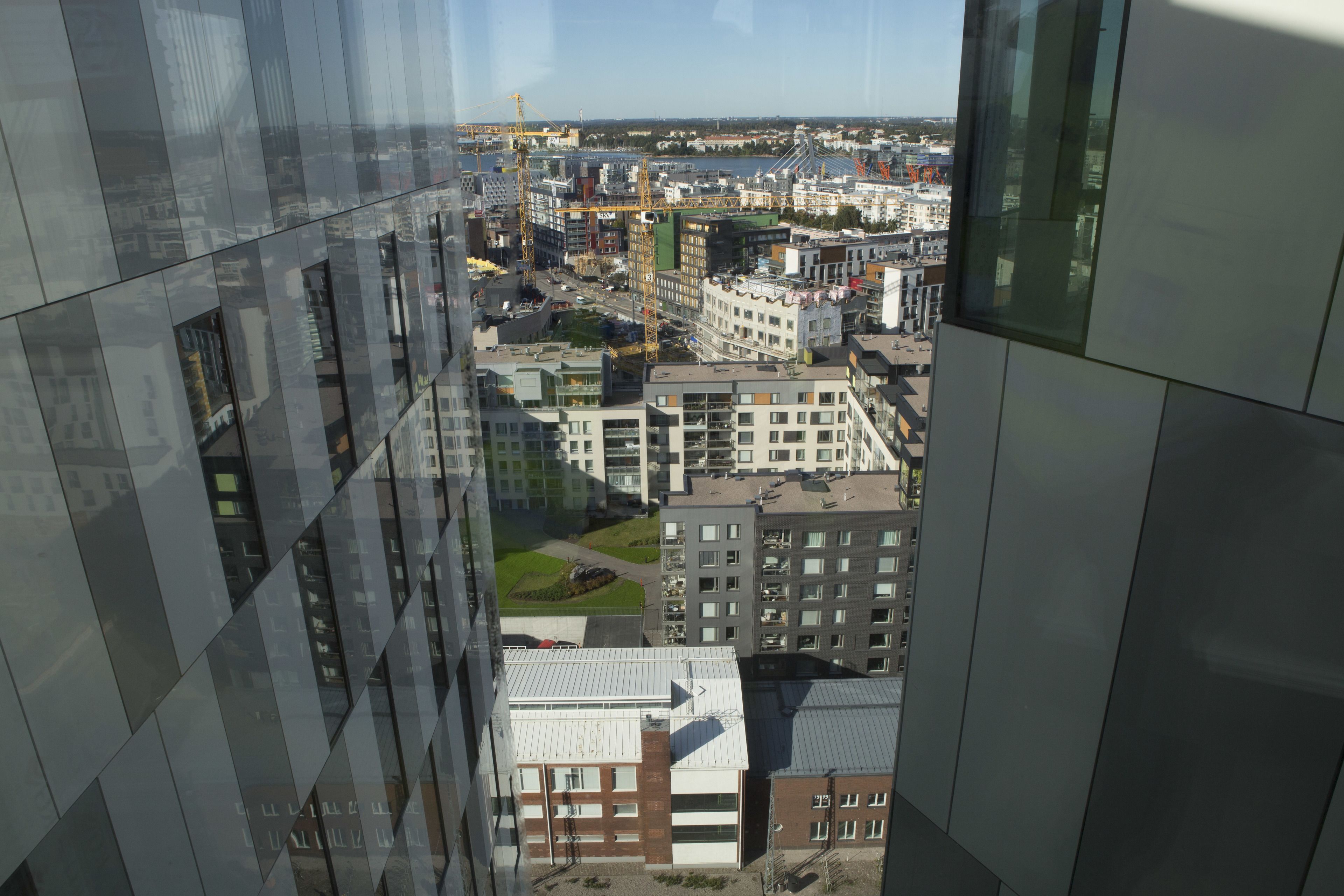 A high-rise building with a view of a cityscape, including various buildings and construction cranes.
