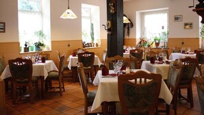 Comedor con varias mesas y sillas, cada conjunto con manteles blancos y cristalería.