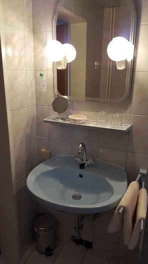 Een badkamer met een wastafel, spiegel en handdoekhouder.