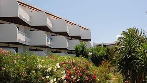 Un bâtiment moderne doté de nombreux balcons et d’un jardin agrémenté de diverses plantes et fleurs.