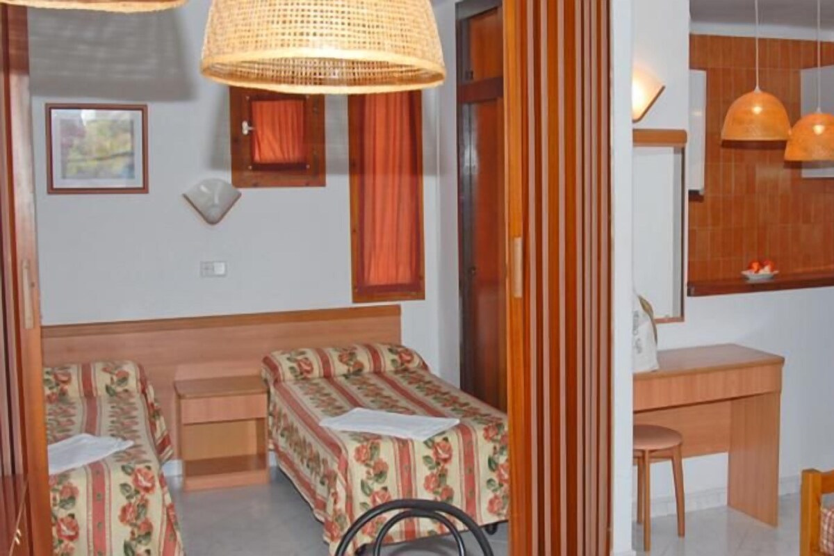 A room with two single beds, a desk, and a chair.