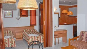 Une chambre d’hôtel de taille réduite, comprenant un lit, un bureau et une petite table à manger.