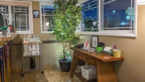 A hotel reception area with a wooden desk, a plant, a trash bin, and a sign indicating a free press shop. - Gateway Inn (Grangeville)
