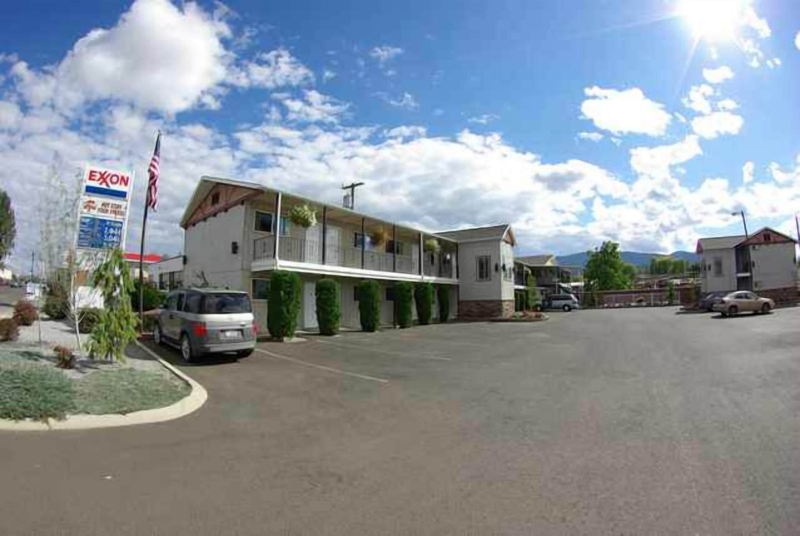 A motel with a single-story structure, a parking lot, and a sign for Exxon gas station.