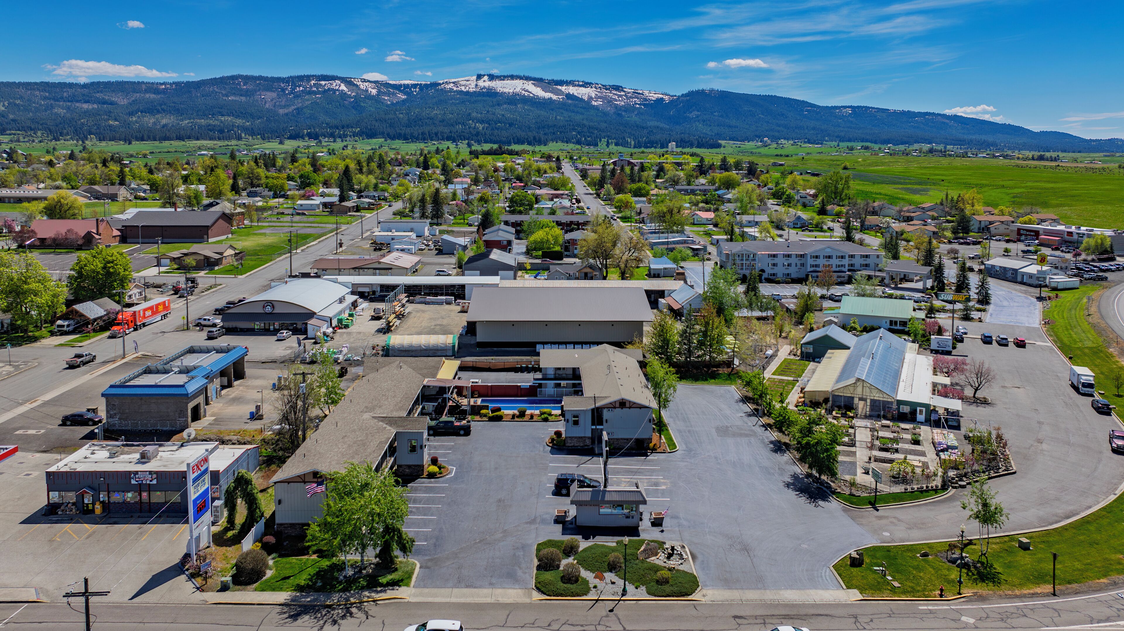 Une zone commerciale dotée d’un grand parking, de bâtiments industriels et, en arrière-plan, d’une chaîne de montagnes.