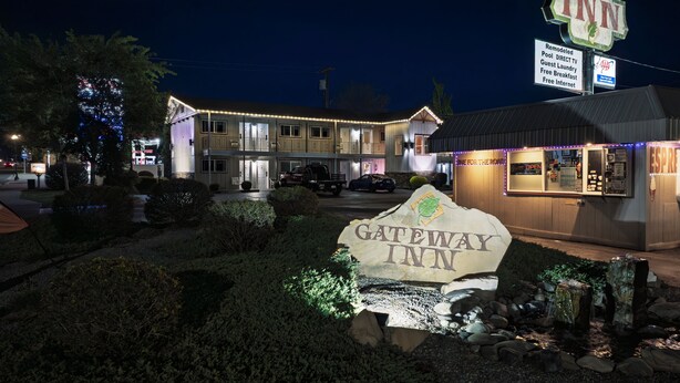 A Gateway Inn with a well-lit entrance, a signboard, and a small adjacent building with a neon sign. - Gateway Inn (Grangeville)