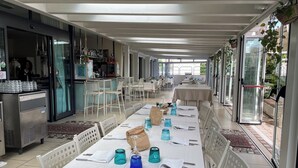 A restaurant with long tables, chairs, and a bar area. - Hotel Franca (Cervia)