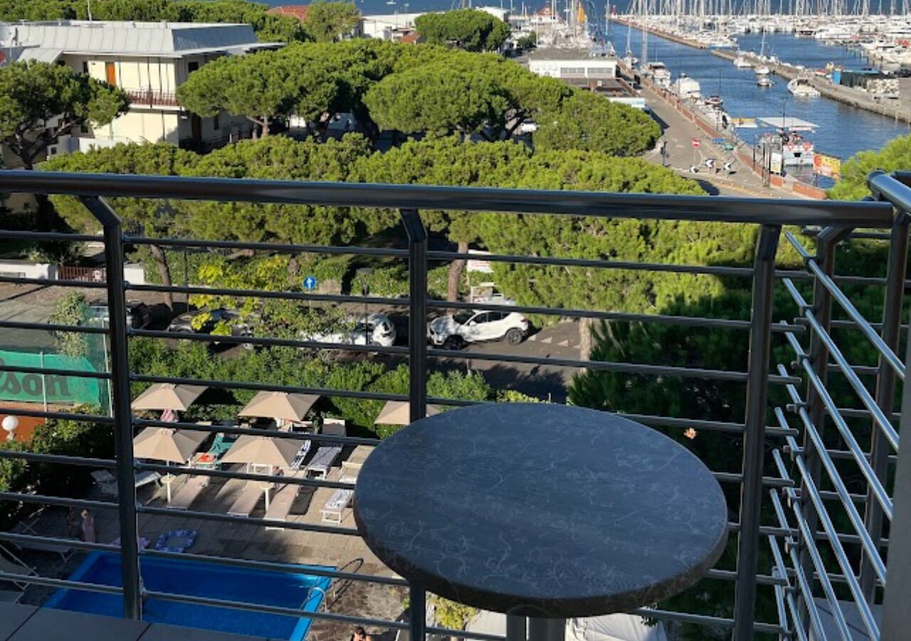 Un balcon avec une table ronde, donnant sur un port de plaisance avec des bateaux et sur le paysage urbain.
