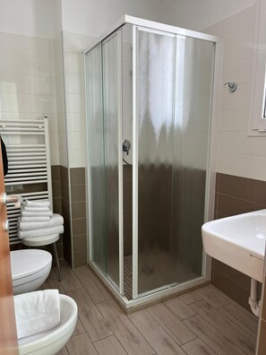 A bathroom with a glass-enclosed shower, a white sink, and a toilet. - Hotel Franca (Cervia)