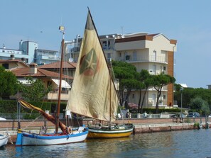 A sailboat docked at a marina with buildings in the background. - Hotel Franca (Cervia)