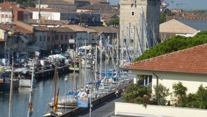A marina with boats docked, a tower, and buildings with a church spire in the background. - Hotel Franca (Cervia)