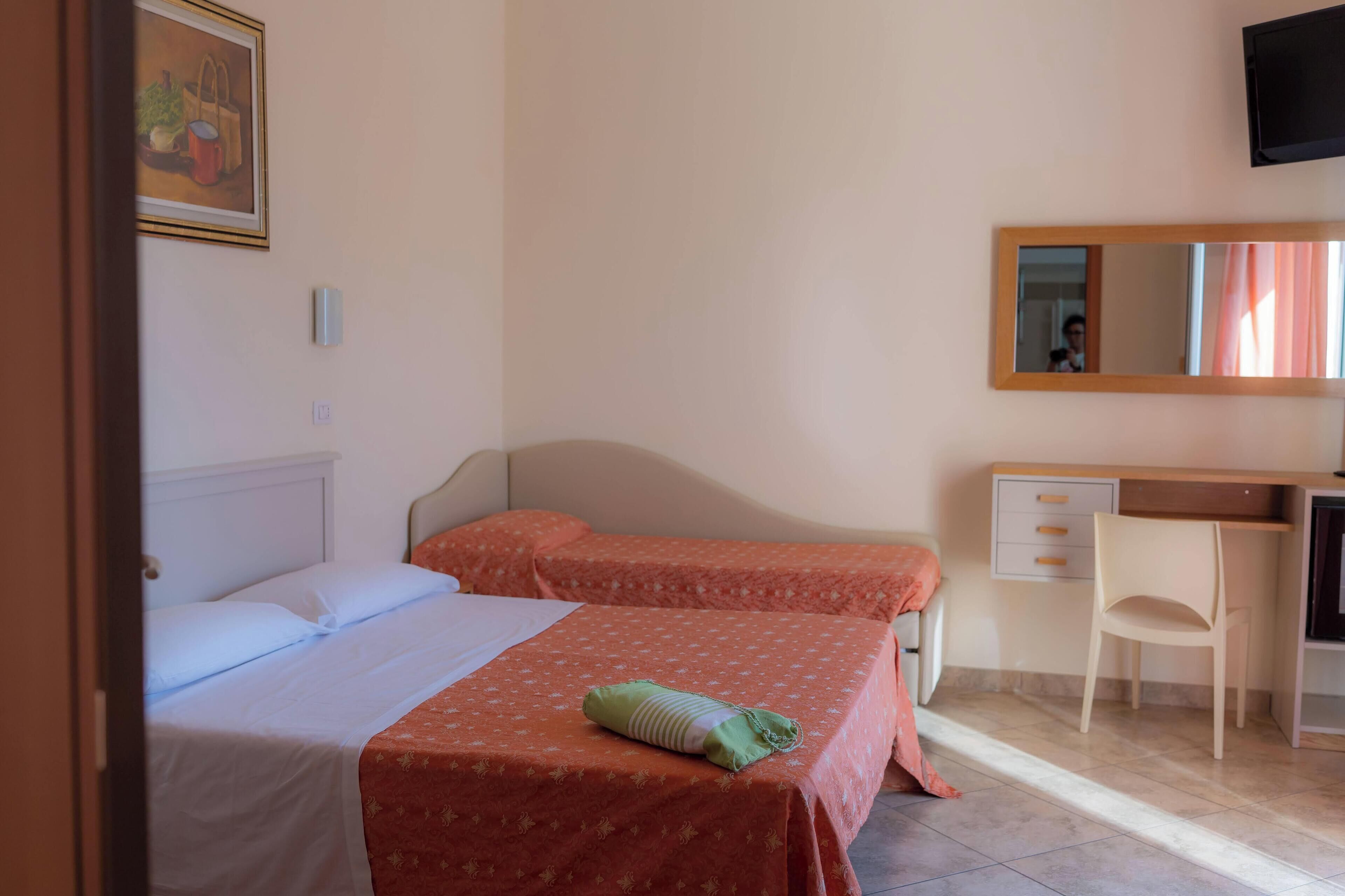 A bedroom with two beds, a desk, and a chair.