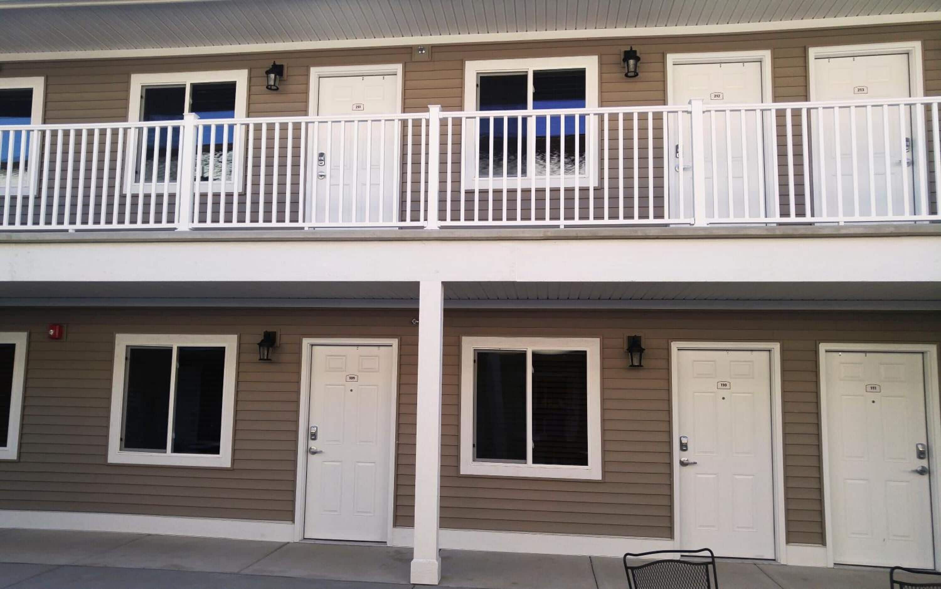 A two-story building with a balcony, multiple doors, and windows.
