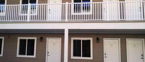 A two-story building with a balcony, multiple doors, and windows.