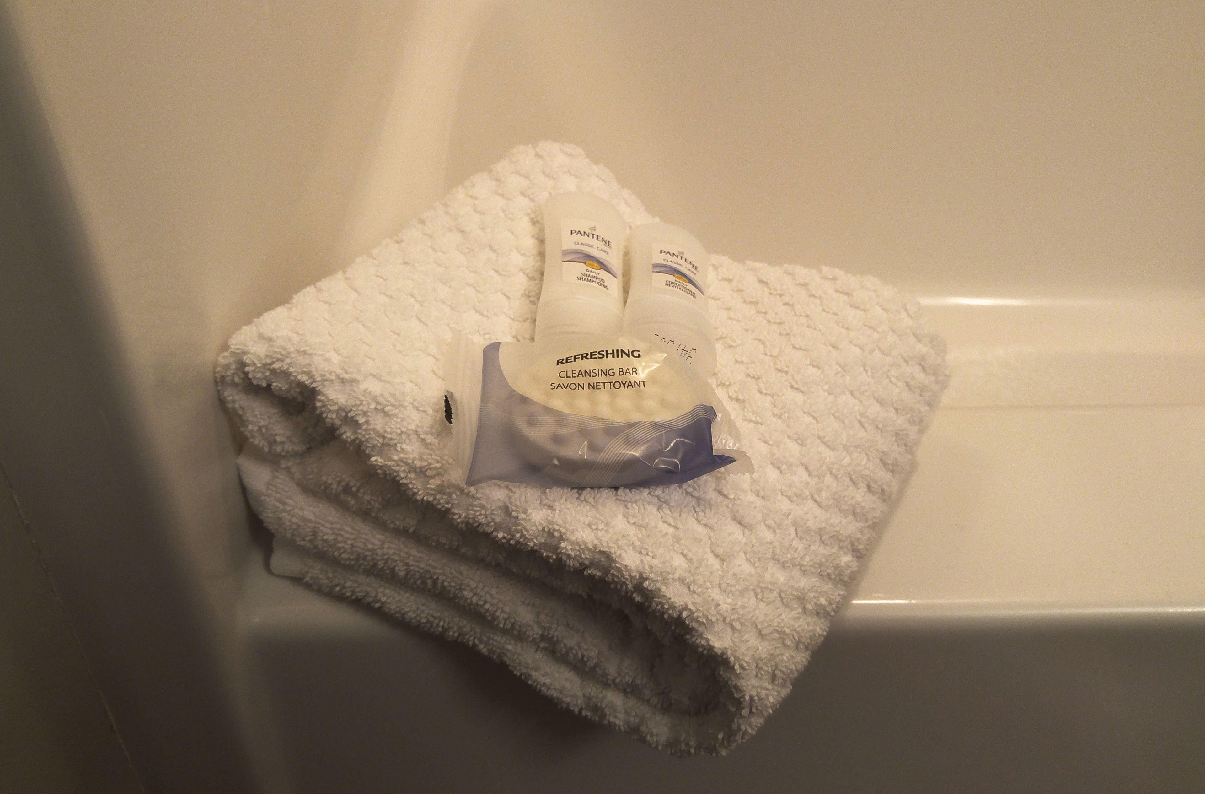 A white towel folded on a bathtub.