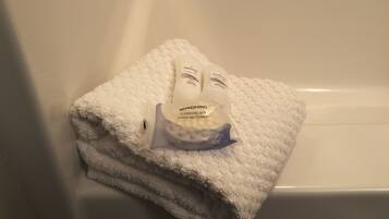A white towel folded on a bathtub.