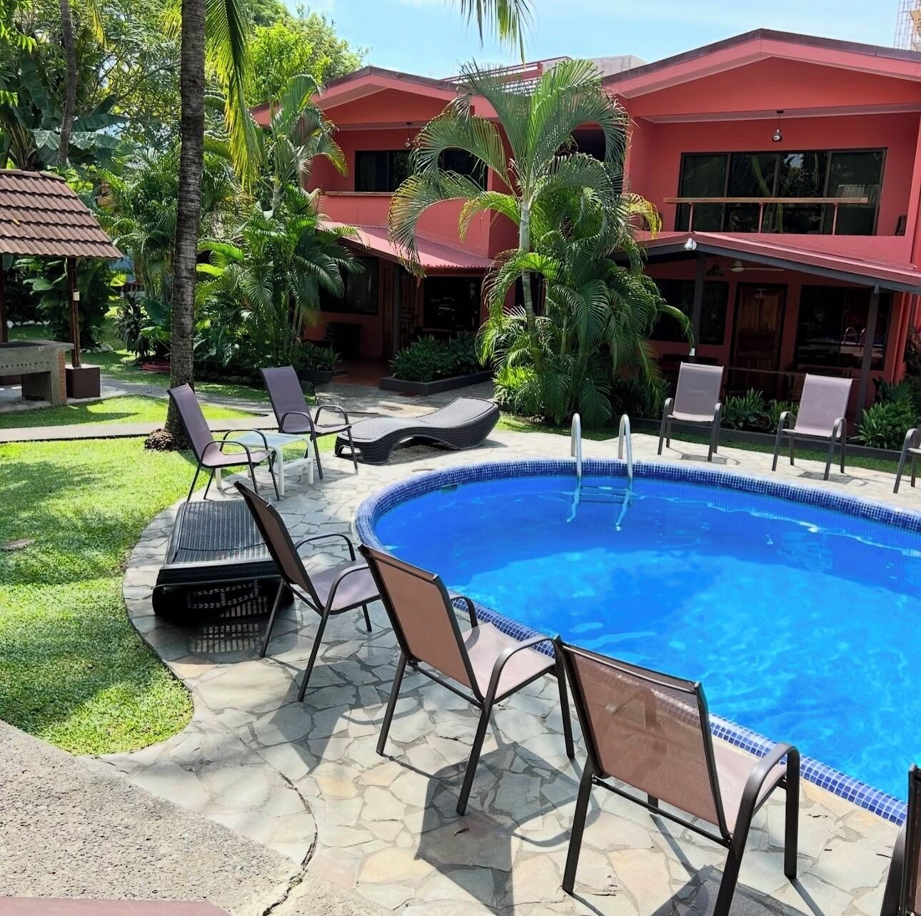 Une piscine avec des chaises longues et, en arrière-plan, un bâtiment rouge.