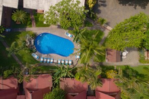 An aerial view of a swimming pool surrounded by palm trees and lounge chairs.
