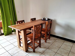 A wooden dining table with four chairs, a small table lamp, and a few cups and saucers on the table.