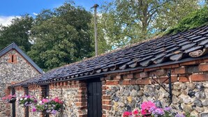 A stone building with a tiled roof, stone walls, and hanging flower baskets. - Grange Farm House (Thetford)