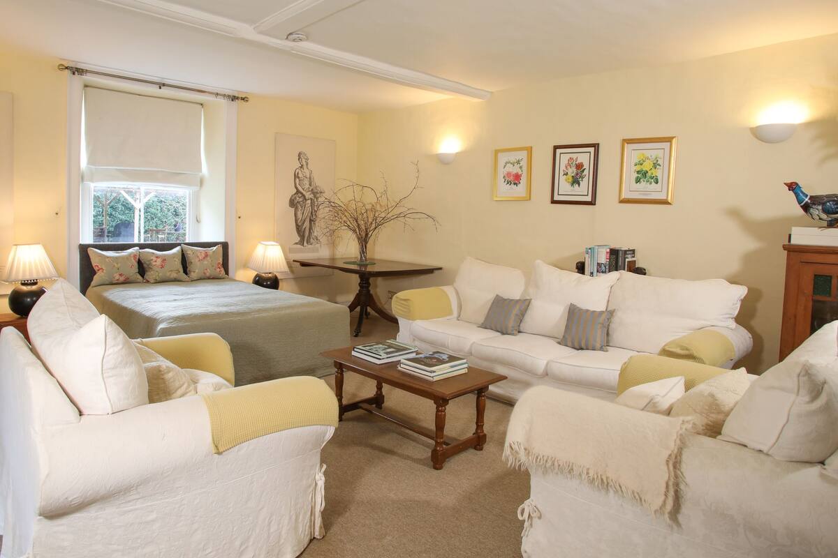 A well-lit living room with a bed, two sofas, a coffee table, and a lamp.