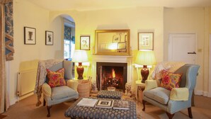 A cozy living room with two armchairs, a fireplace, and a bookshelf. - Grange Farm House (Thetford)