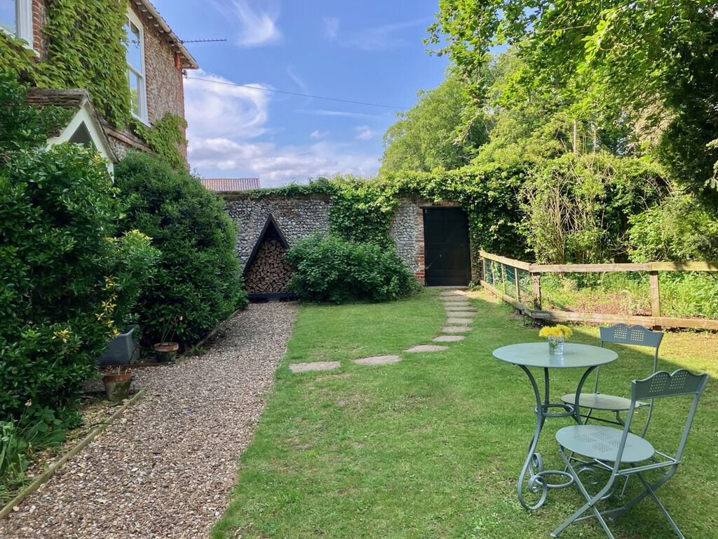 A garden with a stone wall, a gravel path, and a table with chairs.