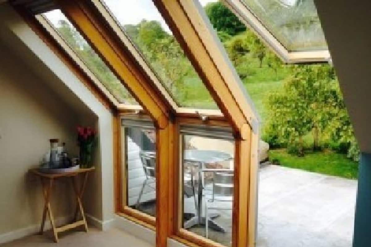 A room with a sloped ceiling and a large glass door leading to an outdoor patio.