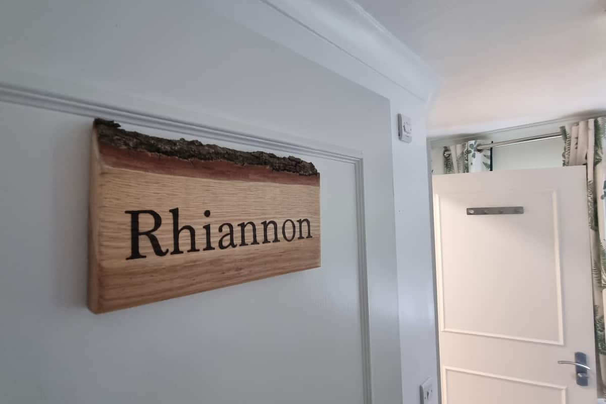A wooden sign with the name "Rhiannon" on a white wall.