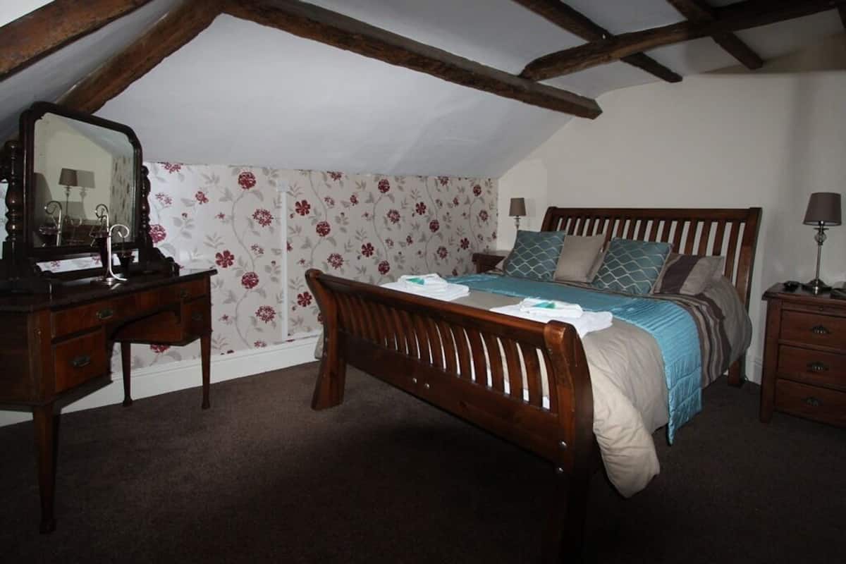 A bedroom with a wooden bed, a dresser, a nightstand, and a mirror.