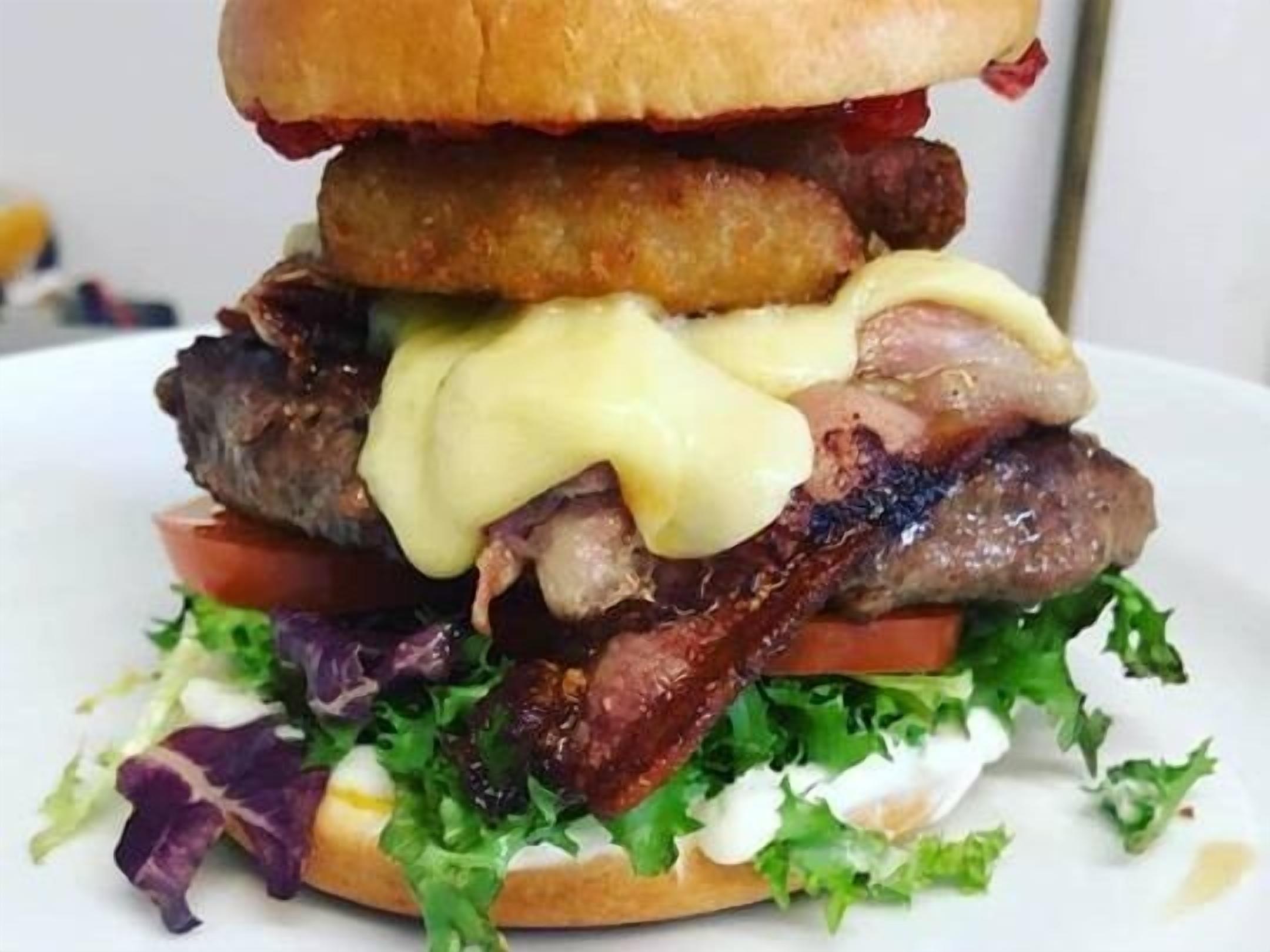 Un hamburger garni de divers ingrédients et accompagné d’une salade.