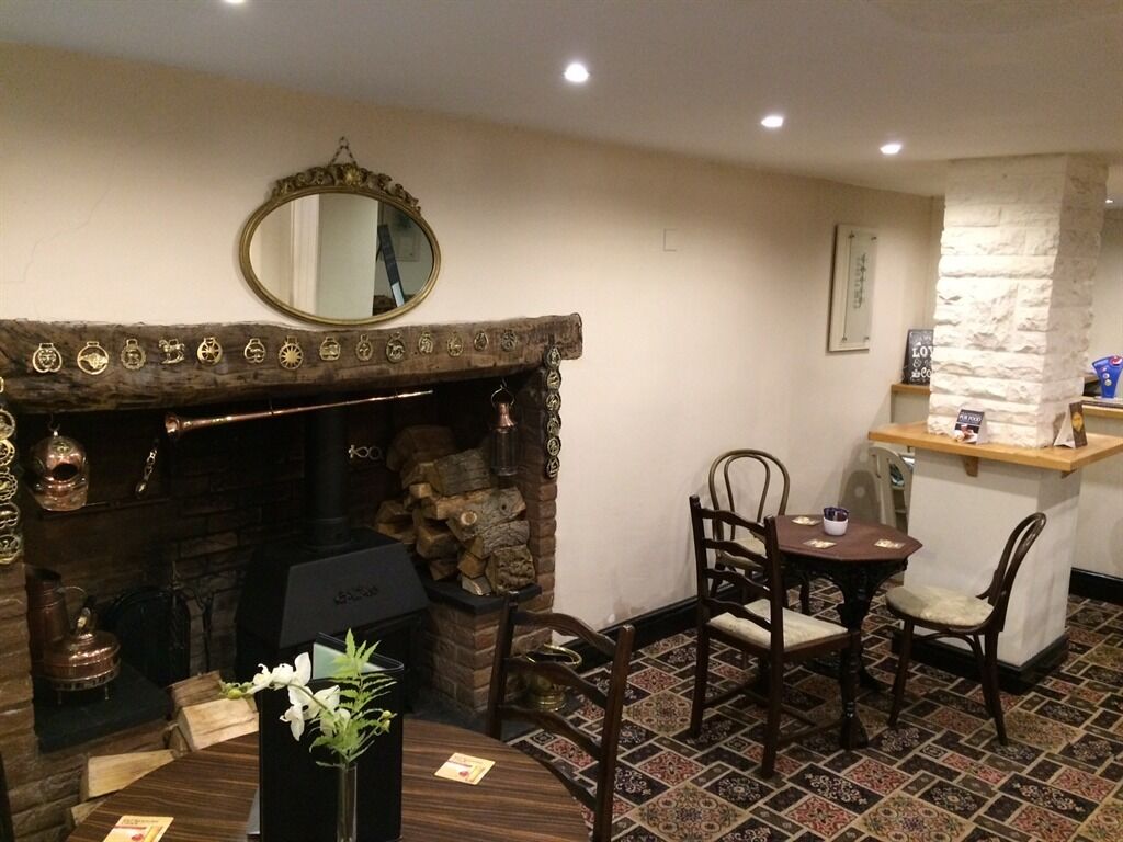 Una habitación acogedora con chimenea, un espejo, una mesa de comedor con sillas y una pequeña zona de bar.