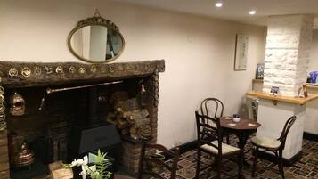 Una habitación acogedora con chimenea, un espejo, una mesa de comedor con sillas y una pequeña zona de bar.