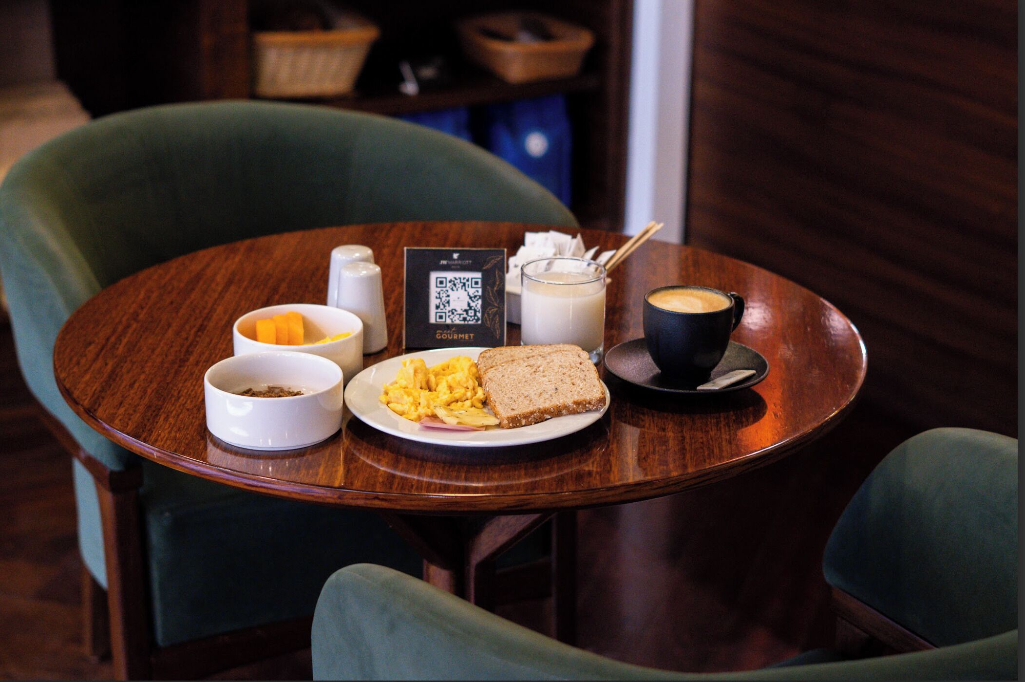 A wooden table with breakfast items including scrambled eggs, toast, coffee, and a QR code.