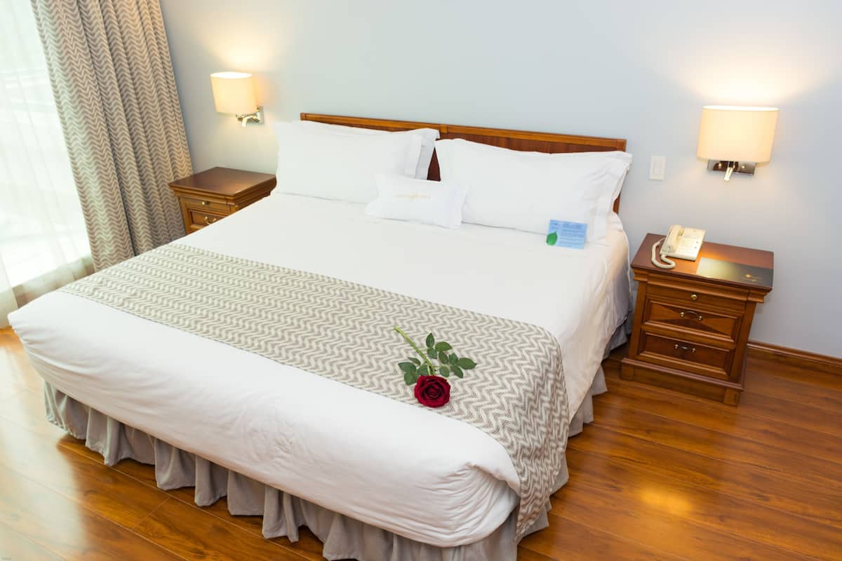 A neatly made bed with a patterned bedspread, a bedside telephone, and a nightstand with a lamp.