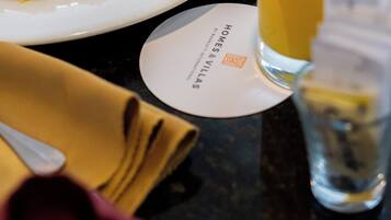 A breakfast setting with scrambled eggs, sausages, toast, and a glass of orange juice on a table.