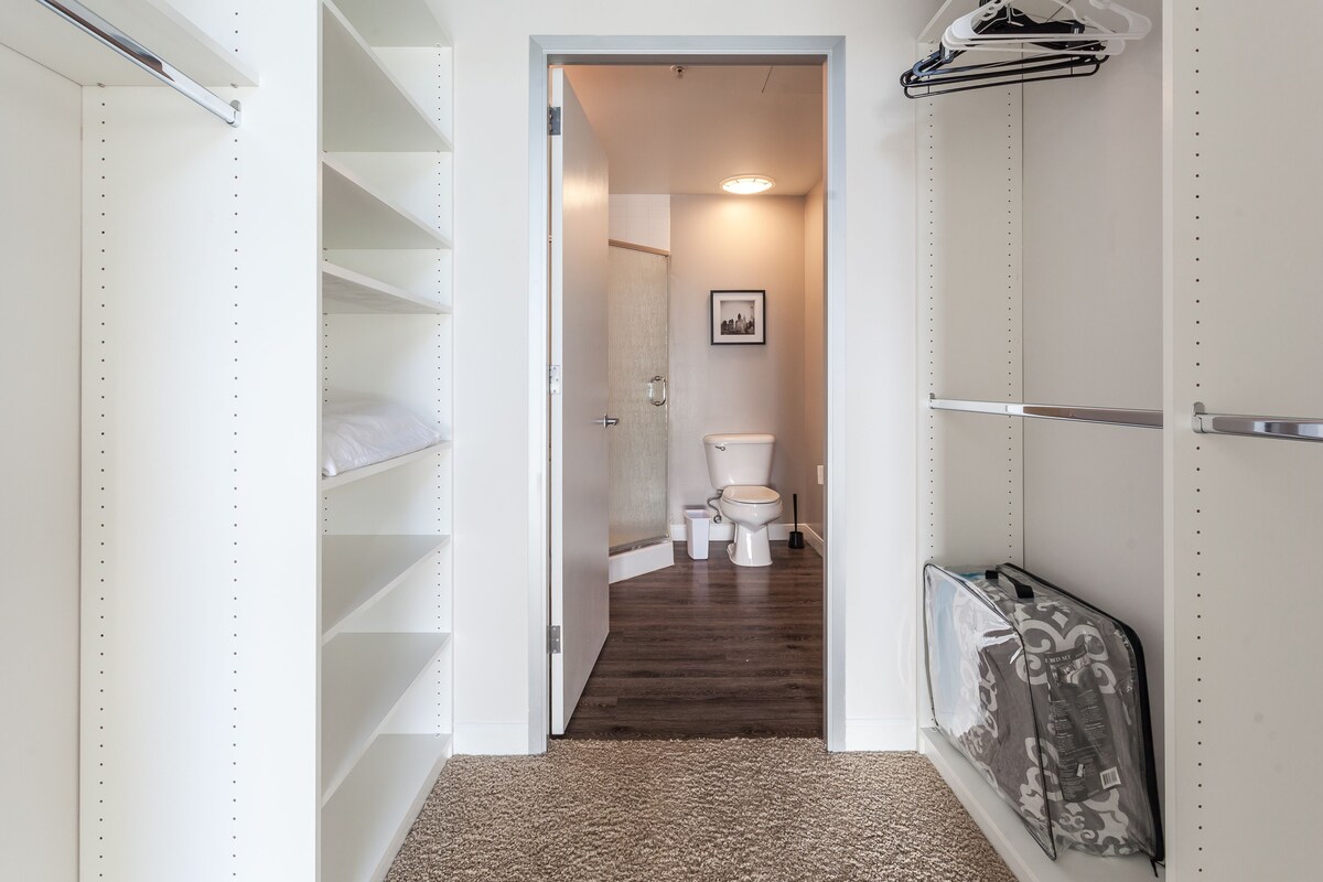 A narrow hallway leading to a bathroom with a toilet, a sink, and a shower.