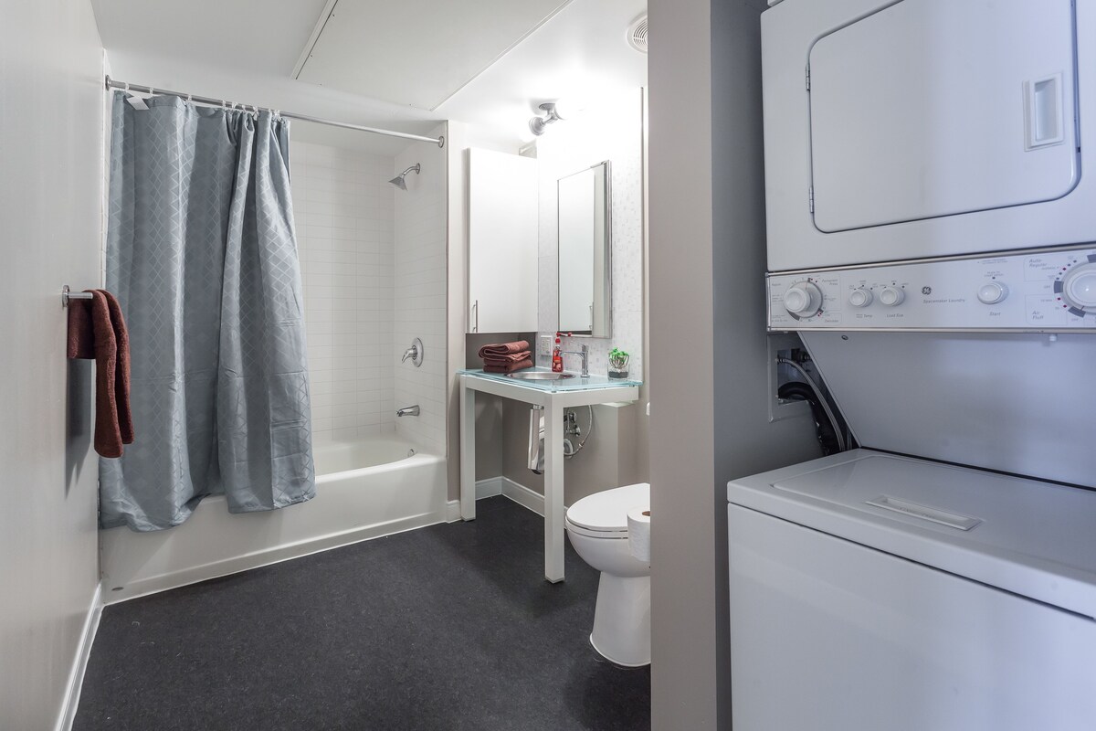 A modern bathroom with a bathtub, toilet, and a washing machine.
