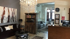 A living room with a chandelier, a sofa, a coffee table, a bookshelf, and a fireplace. - Casa Monraz (Guadalajara)